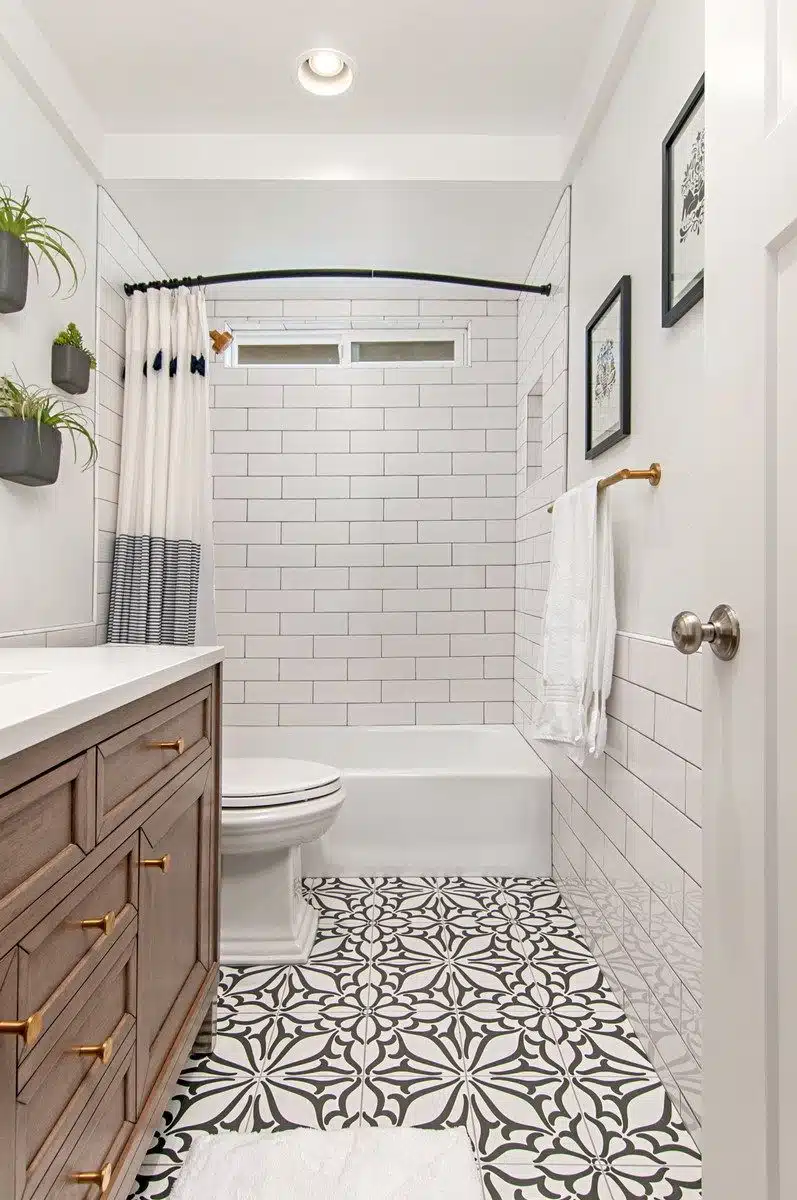 Bathroom with bathtub, white subway tile walls, wood vanity and patterned black-and-white floor